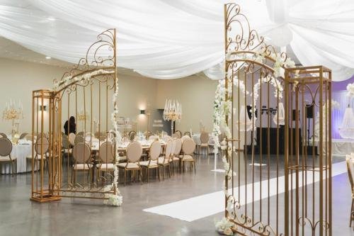 Grande salle de réception mariage avec arches dorées et voilages blancs