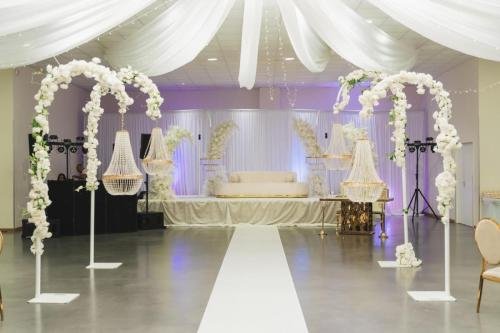Grande salle de réception de mariage décorée arches florales et lustres